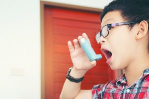Garoto usando uma bombinha para asma em casa